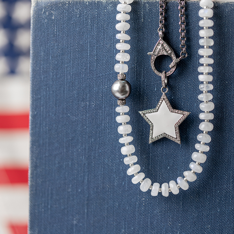 Diamond and Enamel Star on diamond clasp chain and moonstone necklace onJuly 4th background